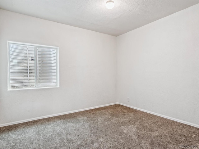 empty room with a textured ceiling, carpet, and baseboards