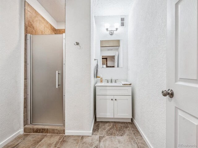 bathroom with a textured wall, a stall shower, vanity, and visible vents