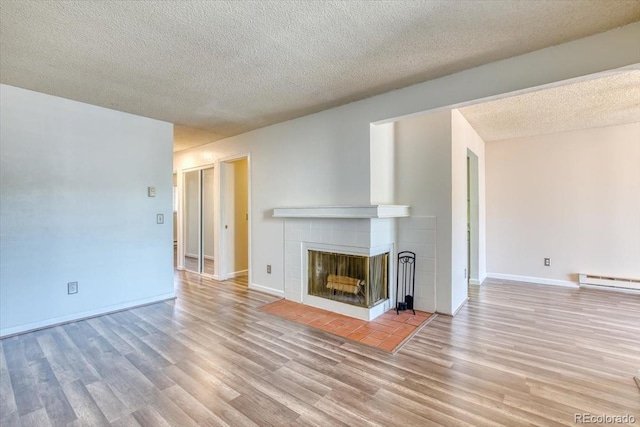 6007 Yarrow St Unit D, Arvada, CO 80004 - unfurnished living room featuring wood finished floors, a tiled fireplace, and a textured ceiling