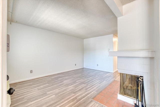 6007 Yarrow St Unit D, Arvada, CO 80004 - unfurnished living room featuring a tile fireplace, a textured ceiling, and wood finished floors