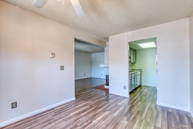 6007 Yarrow St Unit D, Arvada, CO 80004 - empty room with wood finished floors, ceiling fan, a multi sided fireplace, and a textured ceiling