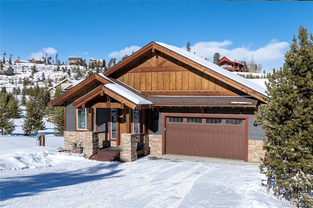 view of front facade featuring stone siding, board and batten siding, and a garage