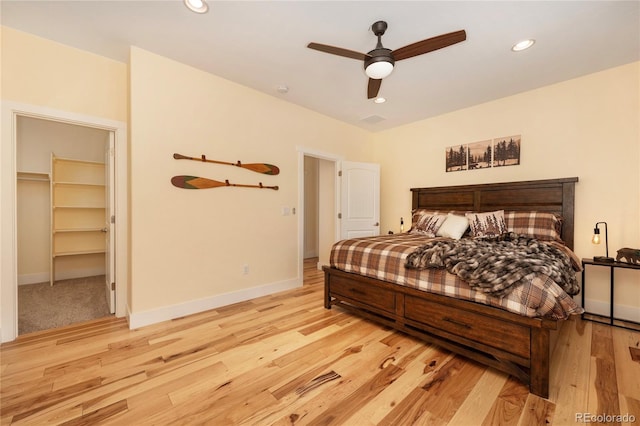 bedroom featuring light hardwood / wood-style floors, a spacious closet, ceiling fan, and a closet