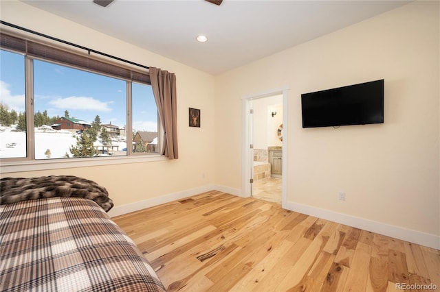 bedroom with ensuite bath and light hardwood / wood-style floors