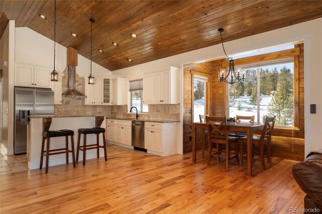 304 Gcr 424, Grand Lake, CO 80447 - kitchen featuring wall chimney range hood, light wood finished floors, a chandelier, stainless steel appliances, and a kitchen bar