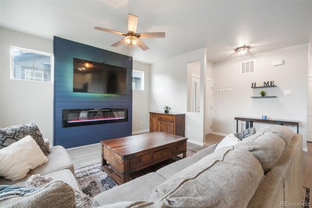 11524 Dewey St, Parker, CO 80138 - living area featuring visible vents, wood finished floors, baseboards, a large fireplace, and a ceiling fan