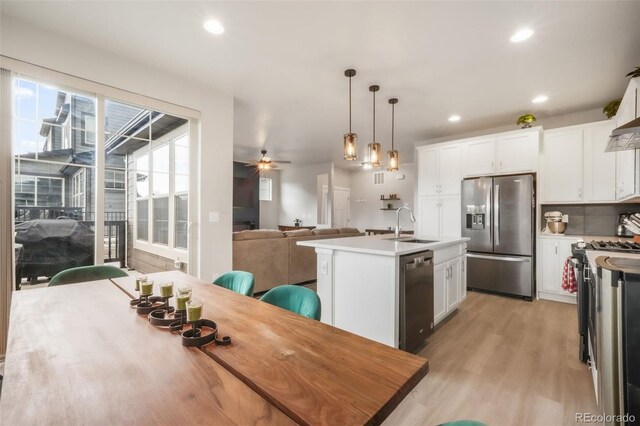 11524 Dewey St, Parker, CO 80138 - kitchen with white cabinets, appliances with stainless steel finishes, a sink, light wood-style floors, and open floor plan