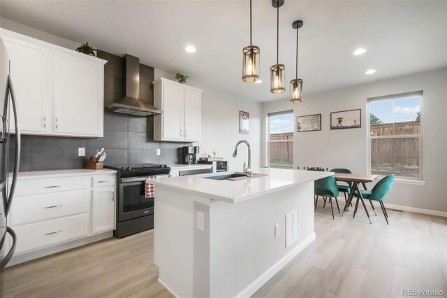 11524 Dewey St, Parker, CO 80138 - kitchen with light wood-style floors, a kitchen island with sink, gas range, wall chimney exhaust hood, and tasteful backsplash