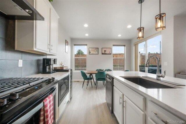 11524 Dewey St, Parker, CO 80138 - kitchen with light wood-type flooring, dishwasher, a sink, under cabinet range hood, and gas range oven