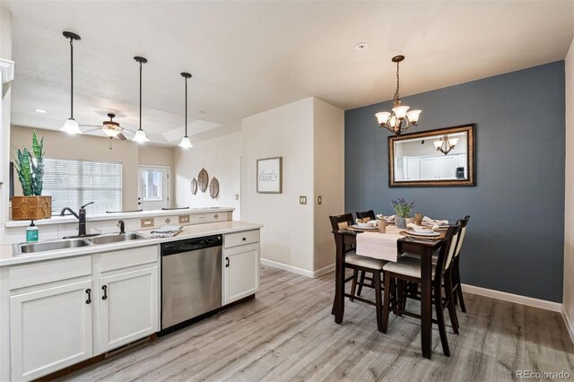kitchen with a sink, stainless steel dishwasher, ceiling fan with notable chandelier, and light wood-type flooring