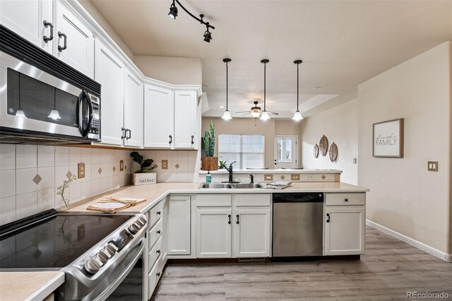 kitchen with ceiling fan, appliances with stainless steel finishes, a sink, light wood-style flooring, and a peninsula