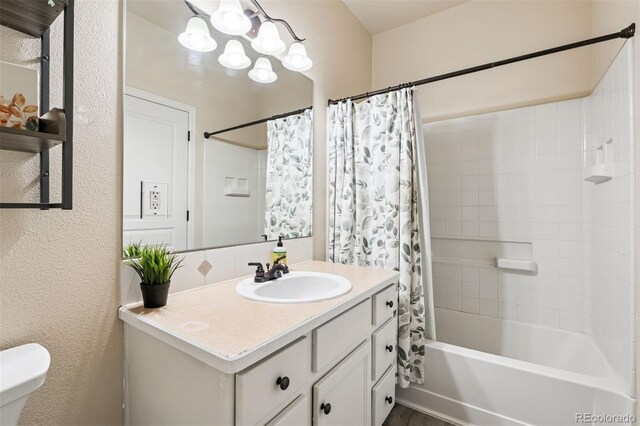full bath with vanity, a textured wall, toilet, and shower / tub combo with curtain