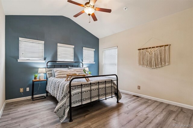 bedroom with wood finished floors, a ceiling fan, baseboards, and lofted ceiling