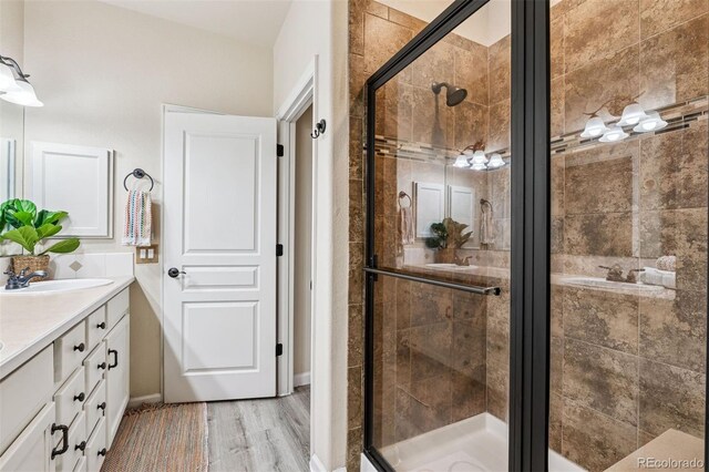 bathroom featuring a shower stall, wood finished floors, and vanity