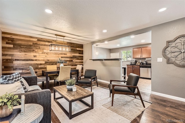 6046 Vrain St, Arvada, CO 80003 - living area with wood walls, recessed lighting, light wood-style floors, a textured ceiling, and baseboards