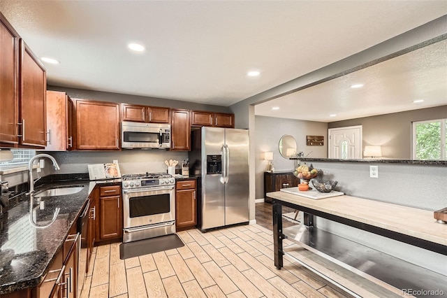 6046 Vrain St, Arvada, CO 80003 - kitchen featuring stainless steel appliances, a sink, recessed lighting, dark stone counters, and light wood-type flooring