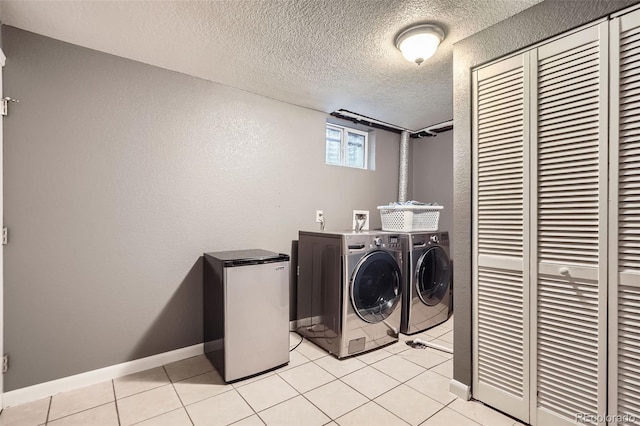 6046 Vrain St, Arvada, CO 80003 - washroom with washing machine and dryer, light tile patterned floors, baseboards, a textured ceiling, and a textured wall