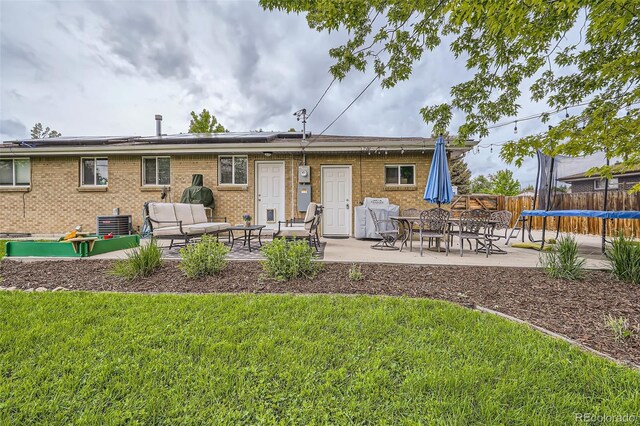 6046 Vrain St, Arvada, CO 80003 - back of property featuring a patio area, a trampoline, an outdoor living space, solar panels, and central AC