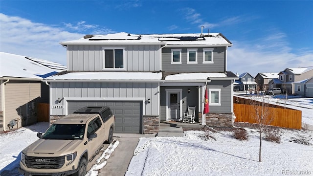 view of front facade with an attached garage, solar panels, fence, and board and batten siding