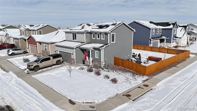 view of front facade featuring a garage, fence, a residential view, and roof mounted solar panels