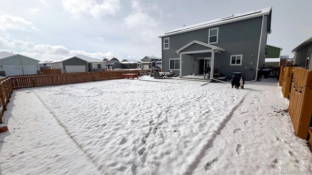 snow covered rear of property with a fenced backyard and a residential view