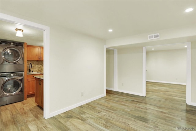 laundry room with stacked washer and clothes dryer, light wood-style floors, recessed lighting, and baseboards