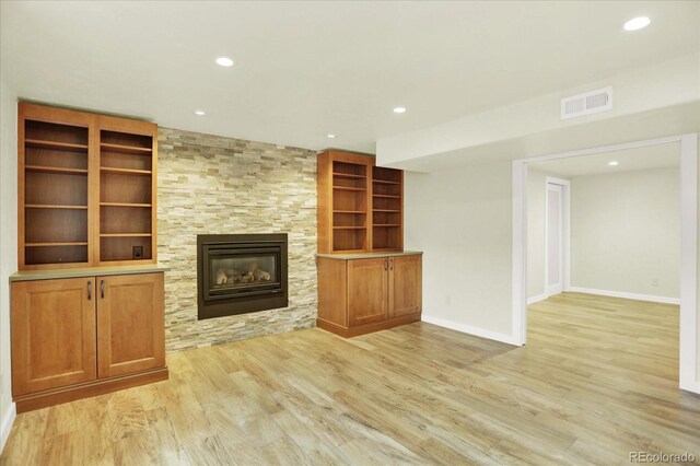 unfurnished living room featuring light wood-style flooring, recessed lighting, a stone fireplace, and baseboards