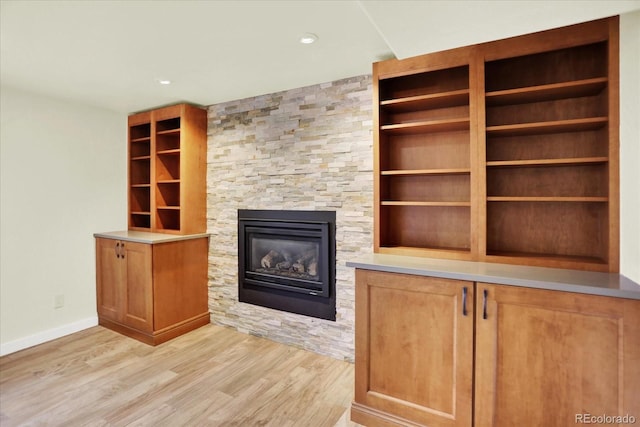unfurnished living room with light wood-type flooring, a fireplace, baseboards, and recessed lighting