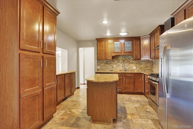 7895 W 67th Ave, Arvada, CO 80004 - kitchen with appliances with stainless steel finishes, stone tile floors, backsplash, a sink, and a kitchen island
