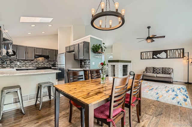 10440 W 83rd Ave, Arvada, CO 80005 - dining room featuring ceiling fan with notable chandelier, wood finished floors, a skylight, and high vaulted ceiling