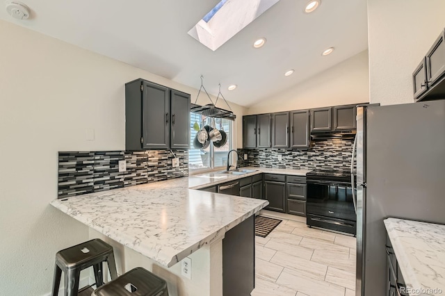 10440 W 83rd Ave, Arvada, CO 80005 - kitchen featuring vaulted ceiling with skylight, backsplash, a sink, a peninsula, and stainless steel appliances