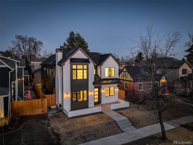 view of front facade featuring a chimney, a gate, a standing seam roof, metal roof, and fence