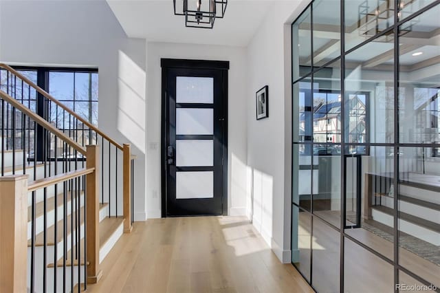 foyer entrance featuring baseboards, stairway, and wood finished floors