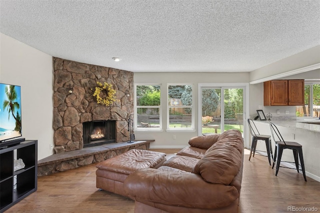 7951 S Webster Way, Littleton, CO 80128 - living room featuring wood finished floors, a textured ceiling, and a stone fireplace
