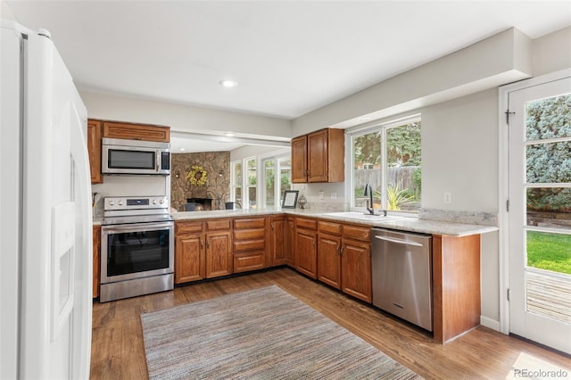 7951 S Webster Way, Littleton, CO 80128 - kitchen featuring stainless steel appliances, wood finished floors, brown cabinetry, and recessed lighting
