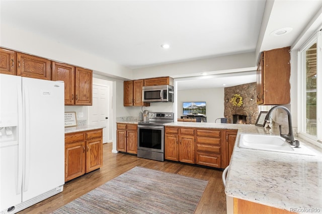 7951 S Webster Way, Littleton, CO 80128 - kitchen with stainless steel appliances, light countertops, a stone fireplace, wood finished floors, and recessed lighting