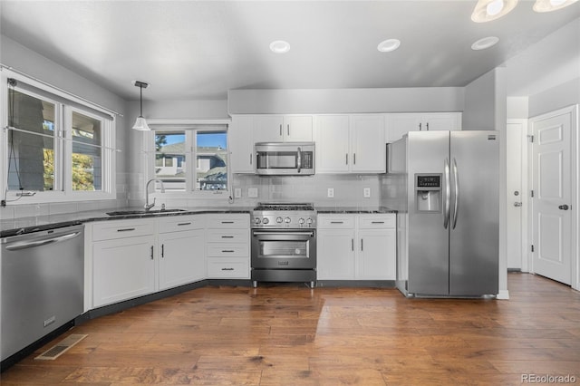 kitchen with pendant lighting, sink, stainless steel appliances, and white cabinets