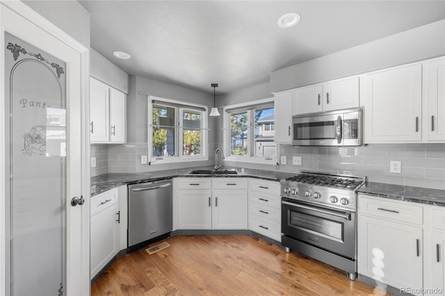 kitchen with sink, decorative light fixtures, light wood-type flooring, appliances with stainless steel finishes, and white cabinets