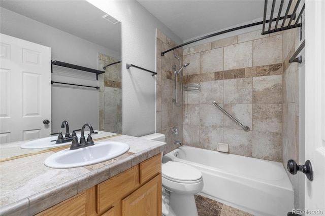 full bathroom featuring vanity, tiled shower / bath, and toilet