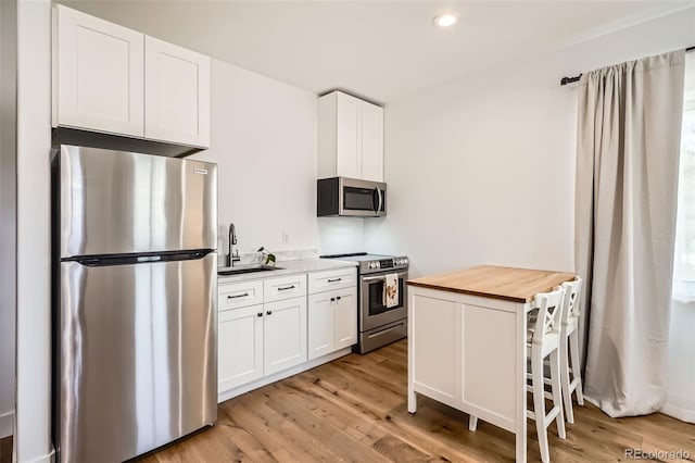 6102 S Aberdeen St, Littleton, CO 80120 - kitchen featuring appliances with stainless steel finishes, a sink, wood counters, light wood-style floors, and recessed lighting
