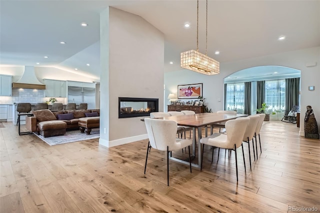 6102 S Aberdeen St, Littleton, CO 80120 - dining space featuring vaulted ceiling, arched walkways, light wood-style floors, recessed lighting, and a multi sided fireplace