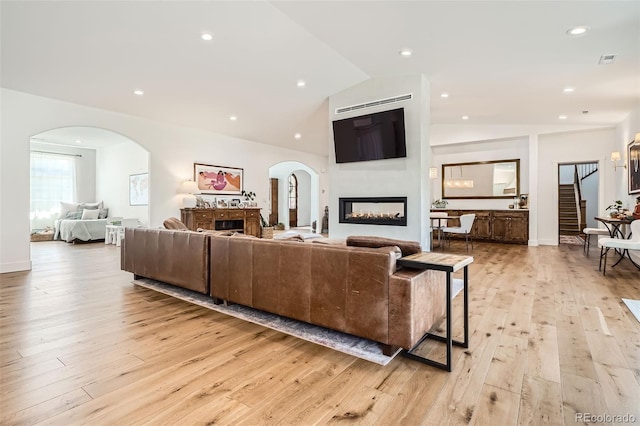6102 S Aberdeen St, Littleton, CO 80120 - living room with a warm lit fireplace, lofted ceiling, light wood finished floors, arched walkways, and recessed lighting
