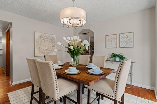 20922 E Crestline Cir, Centennial, CO 80015 - dining room with arched walkways, wood finished floors, baseboards, a textured ceiling, and a chandelier