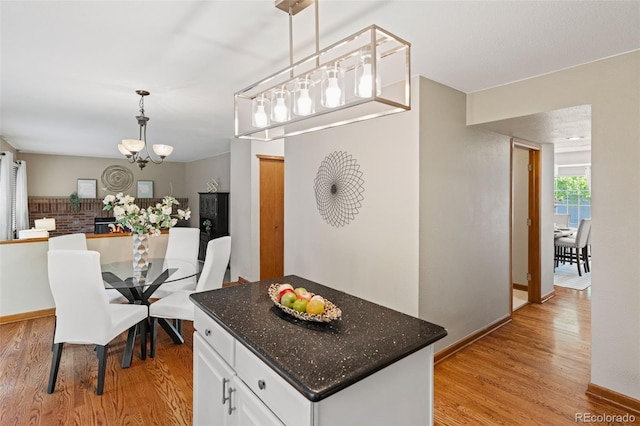 20922 E Crestline Cir, Centennial, CO 80015 - kitchen with light wood finished floors, white cabinets, a chandelier, decorative light fixtures, and dark stone countertops