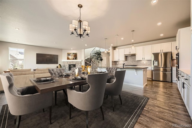 1715 Pioneer Cir, Lafayette, CO 80026 - dining space featuring a chandelier, dark wood finished floors, recessed lighting, and a stone fireplace