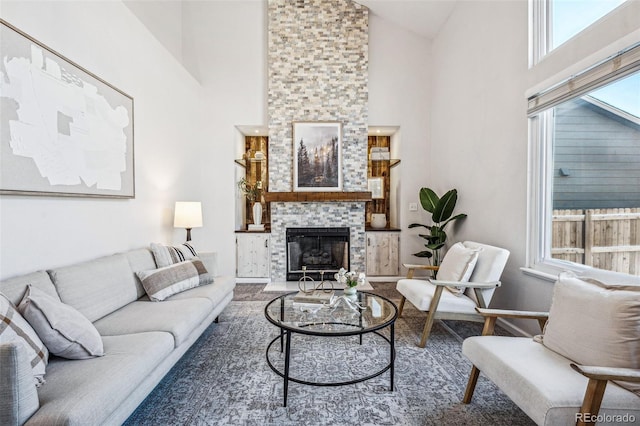 living area with high vaulted ceiling, a fireplace, and baseboards