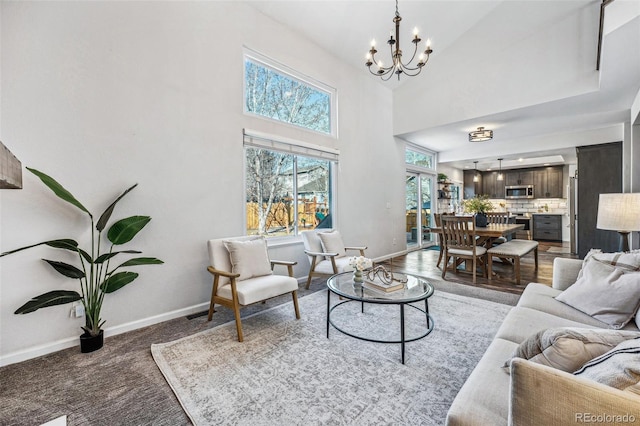 living area featuring a towering ceiling, baseboards, and a chandelier