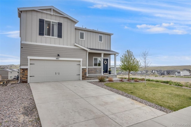 view of front of property with board and batten siding, stone siding, an attached garage, a porch, and driveway