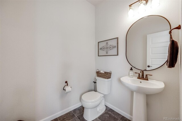 bathroom featuring toilet, baseboards, and tile patterned flooring