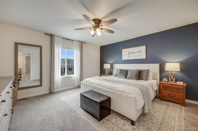 bedroom with light colored carpet, baseboards, and a ceiling fan